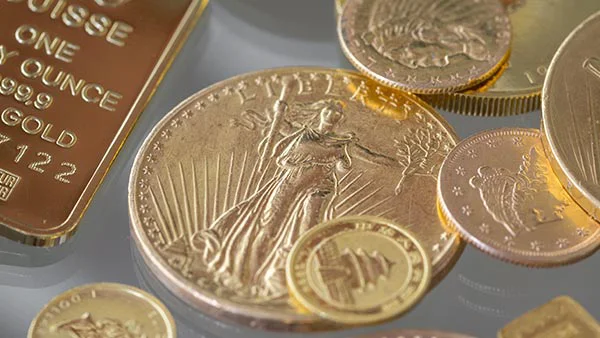 Assortment of gold bullion and collectible coins including American Eagle and PAMP Suisse designs.