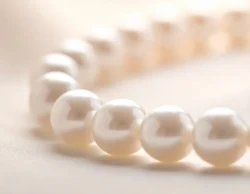 Macro close-up of lustrous white pearls in a necklace, highlighting soft sheen and smooth surface detail.
