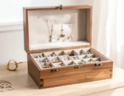 Open wooden jewelry box on dresser with polished rings, necklaces, and earrings neatly arranged, sparkling in natural light.